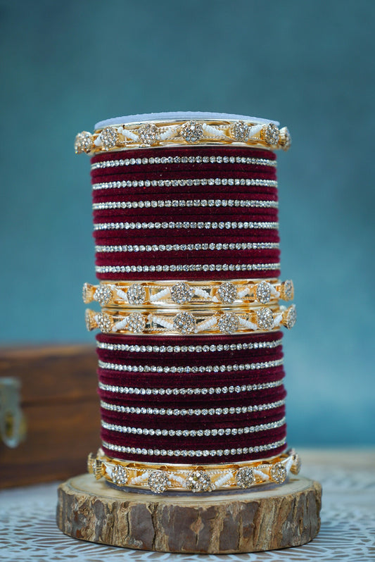 Stack of decorative bangles on a wooden stand with a blue background by hitesh bangles