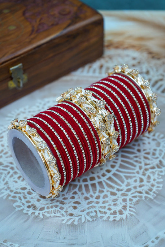 Red and gold bangles on a white doily with a wooden box in the background by hitesh bangles