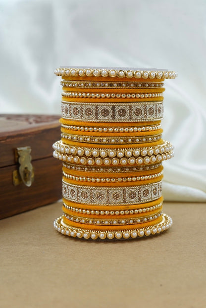 Stack of ornate bangles on a beige surface with a white background by hitesh bangles