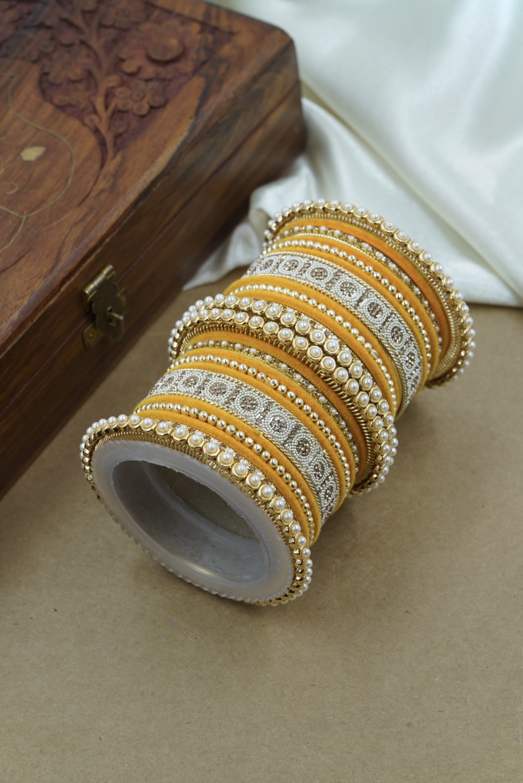 Roll of gold and white beaded ribbon on a wooden surface by hitesh bangles