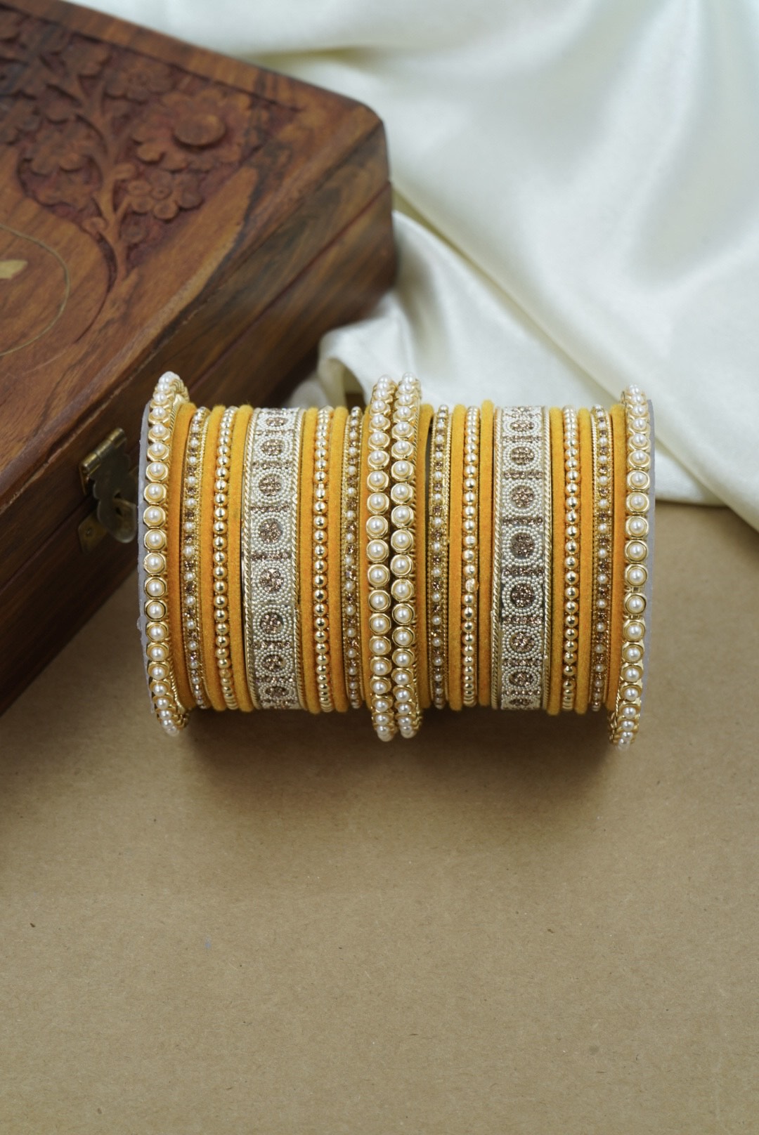 Decorative yellow bangle with intricate patterns on a wooden surface by hitesh bangles