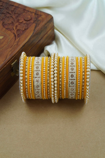 Decorative yellow bangle with intricate patterns on a wooden surface by hitesh bangles