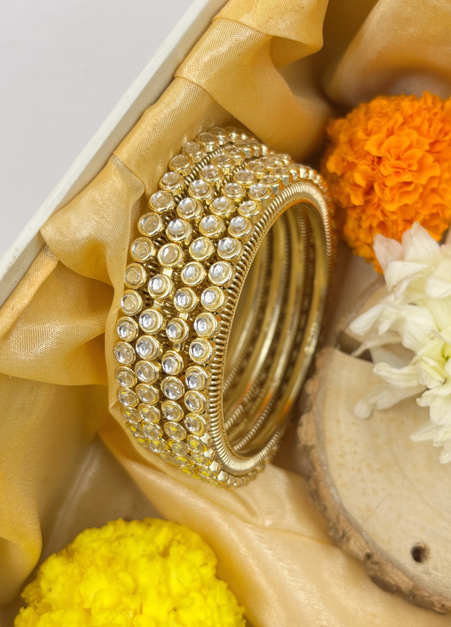 Gold bangles with crystals on a decorative background with flowers by hitesh bangles