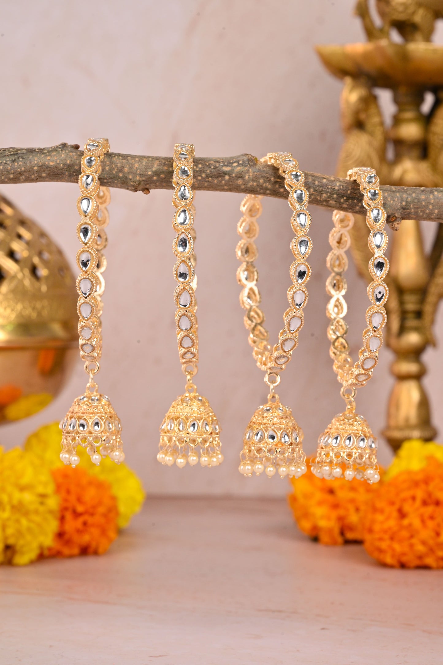 Gold jhumka earrings on a branch with decorative background by hitesh bangles
