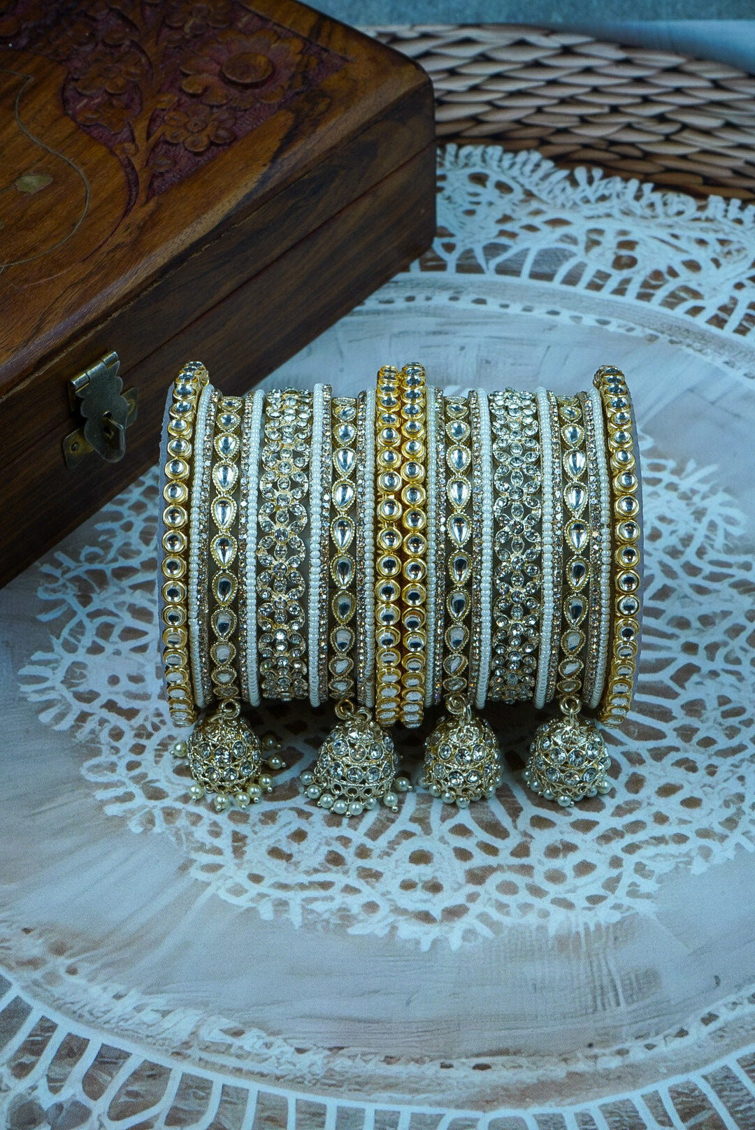 Set of gold and silver bangles with tassels on a textured surface by hitesh bangles