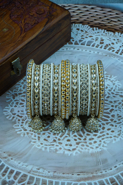 Set of gold and silver bangles with tassels on a textured surface by hitesh bangles