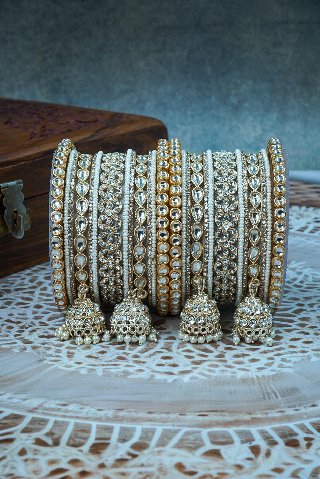 Set of gold and silver bangles with jhumkas on a textured surface by hitesh bangles