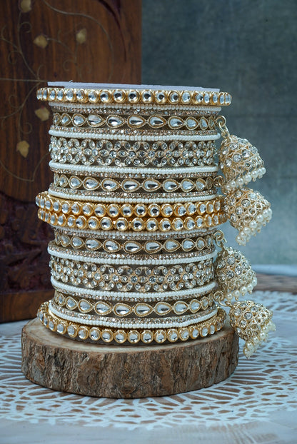 Stack of gold and silver bangles on a wooden block with a neutral background by hitesh bangles