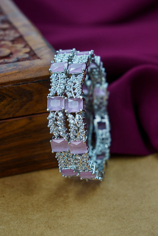 Silver bracelet with pink gemstones on a wooden surface by hitesh bangles