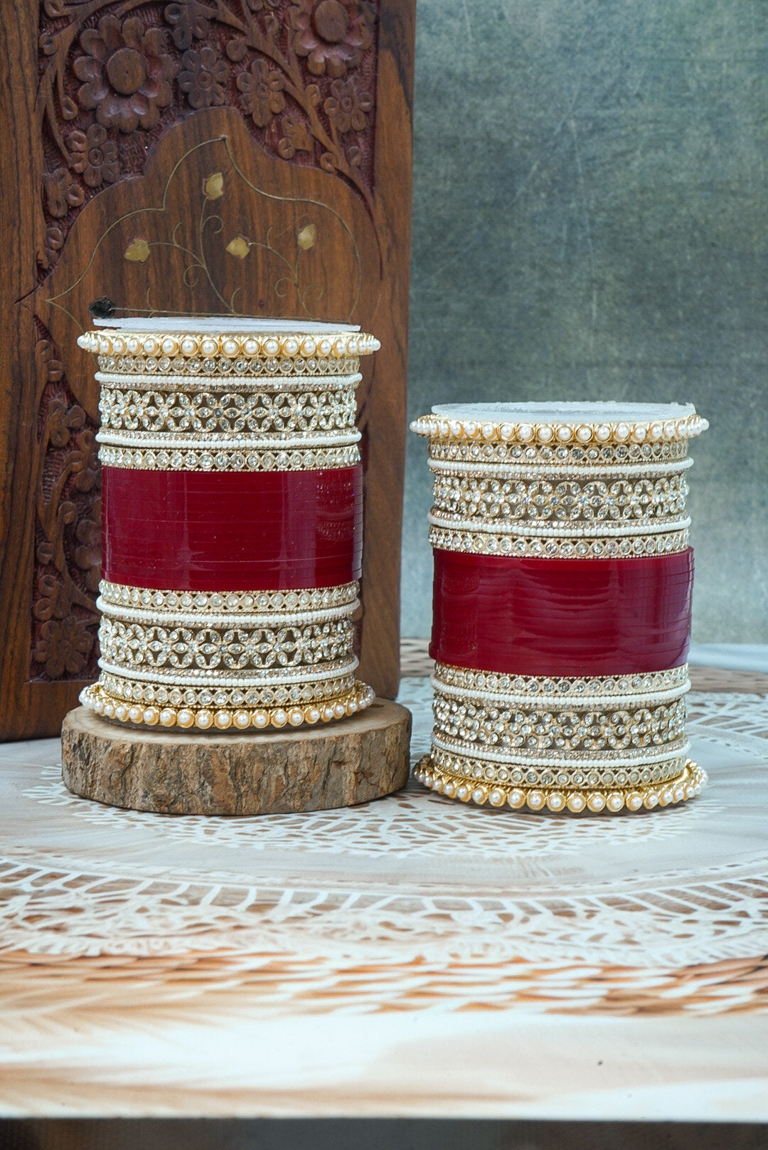 Two decorative containers with red and beige patterns on a wooden surface by hitesh bangles