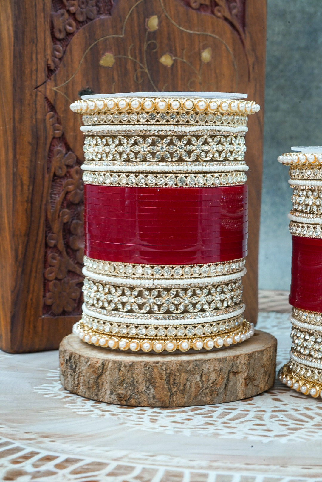 Decorative bangles with red and gold design on a wooden stand by hitesh bangles
