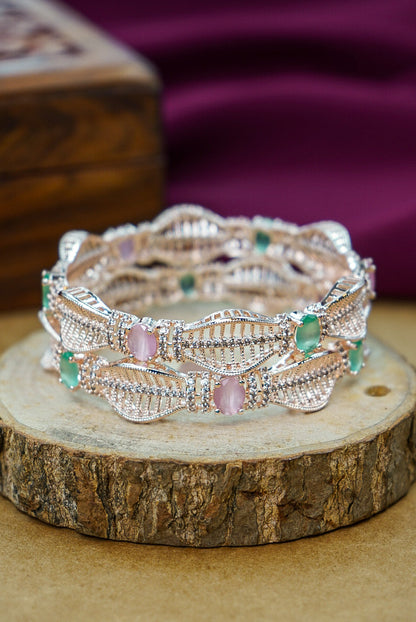 Silver bracelet with pink and green stones on a wooden surface by hitesh bangles