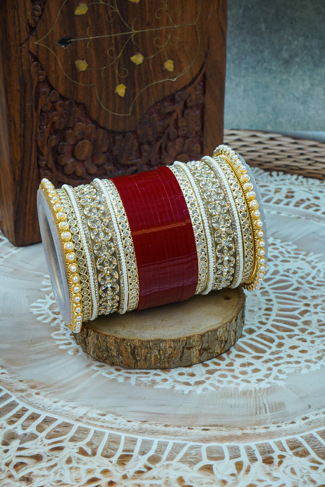 Two ornate bangles stacked on a wooden block with a textured background by hitesh bangles