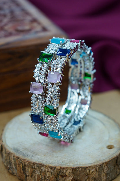 Pair of silver hoop earrings with colorful gemstones on a wooden surface by hitesh bangles