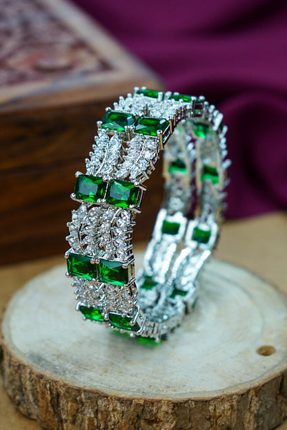 Pair of emerald and diamond earrings on a wooden surface with a blurred background by hitesh bangles