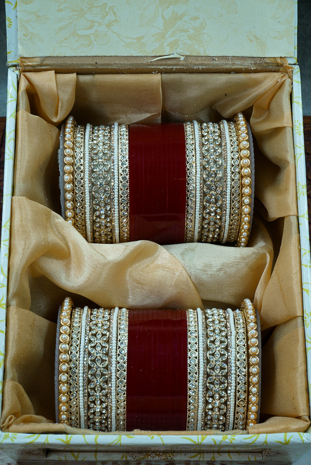 Pair of ornate bangles in a decorative box with gold and red accents by hitesh bangles