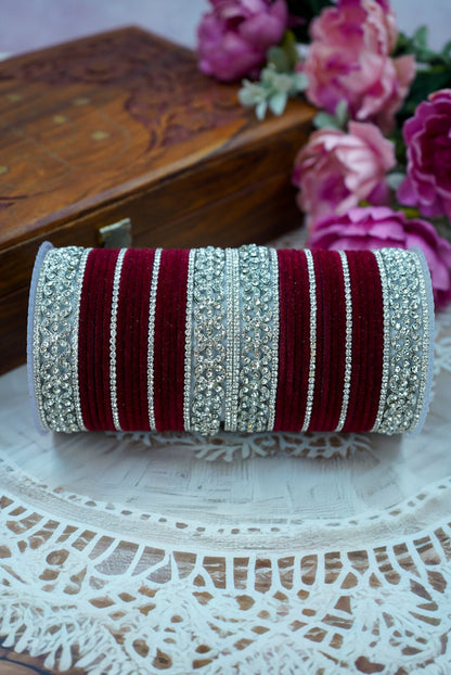 Decorative clutch with red and silver stripes on a lace tablecloth with flowers in the background by hitesh bangles