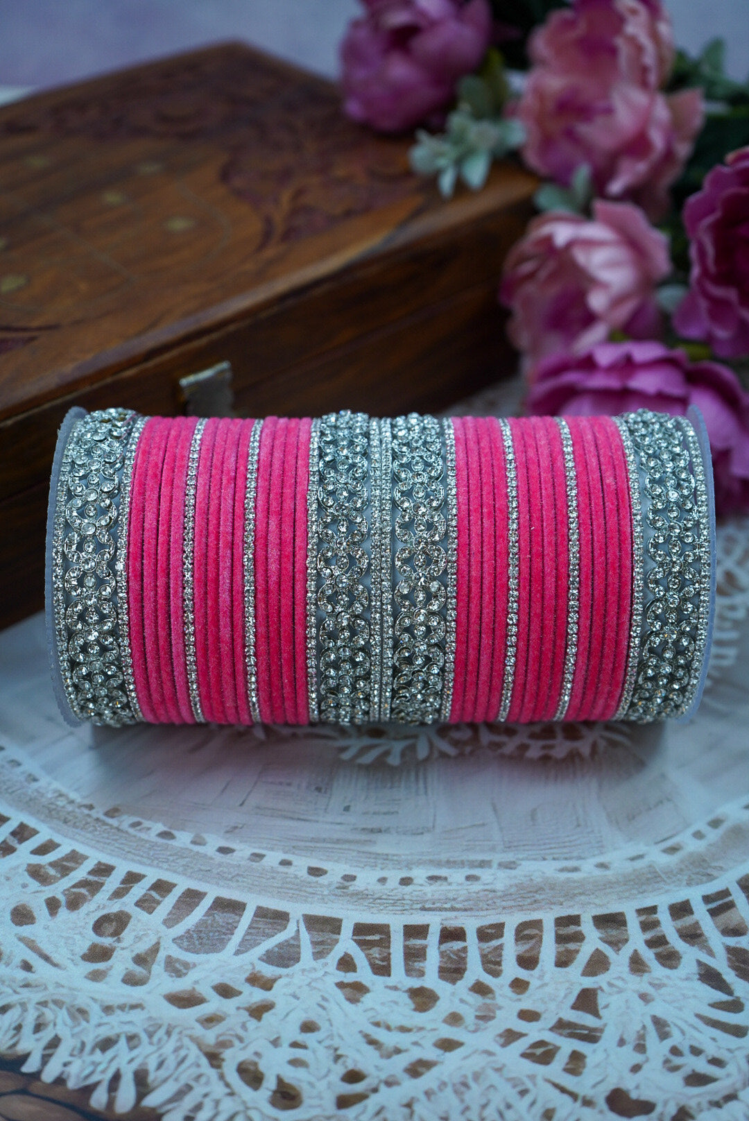 Pink and silver bangles on a decorative plate with flowers in the background by hitesh bangles