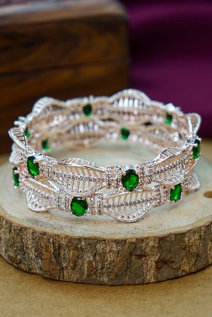 Silver bracelet with green gemstones on a wooden surface by hitesh bangles