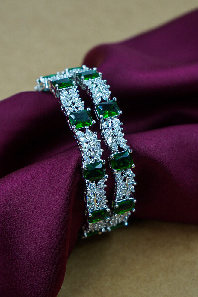 Silver bracelet with green gemstones on a purple fabric background by hitesh bangles