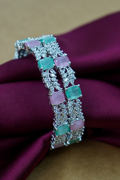 Silver bracelet with green and pink gemstones on a purple fabric background by hitesh bangles