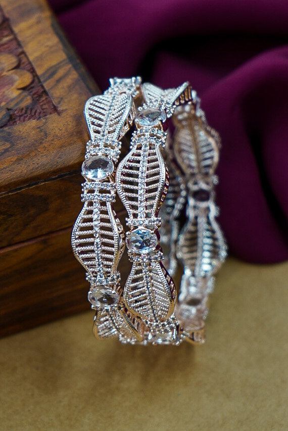 Pair of silver earrings with intricate designs on a wooden surface by hitesh bangles