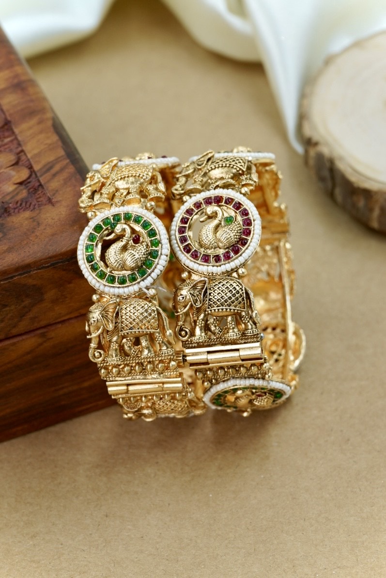 Gold bracelet with intricate designs on a beige surface by hitesh bangles