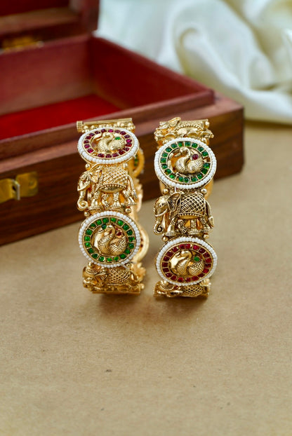 Gold earrings with gemstones on a beige surface by hitesh bangles