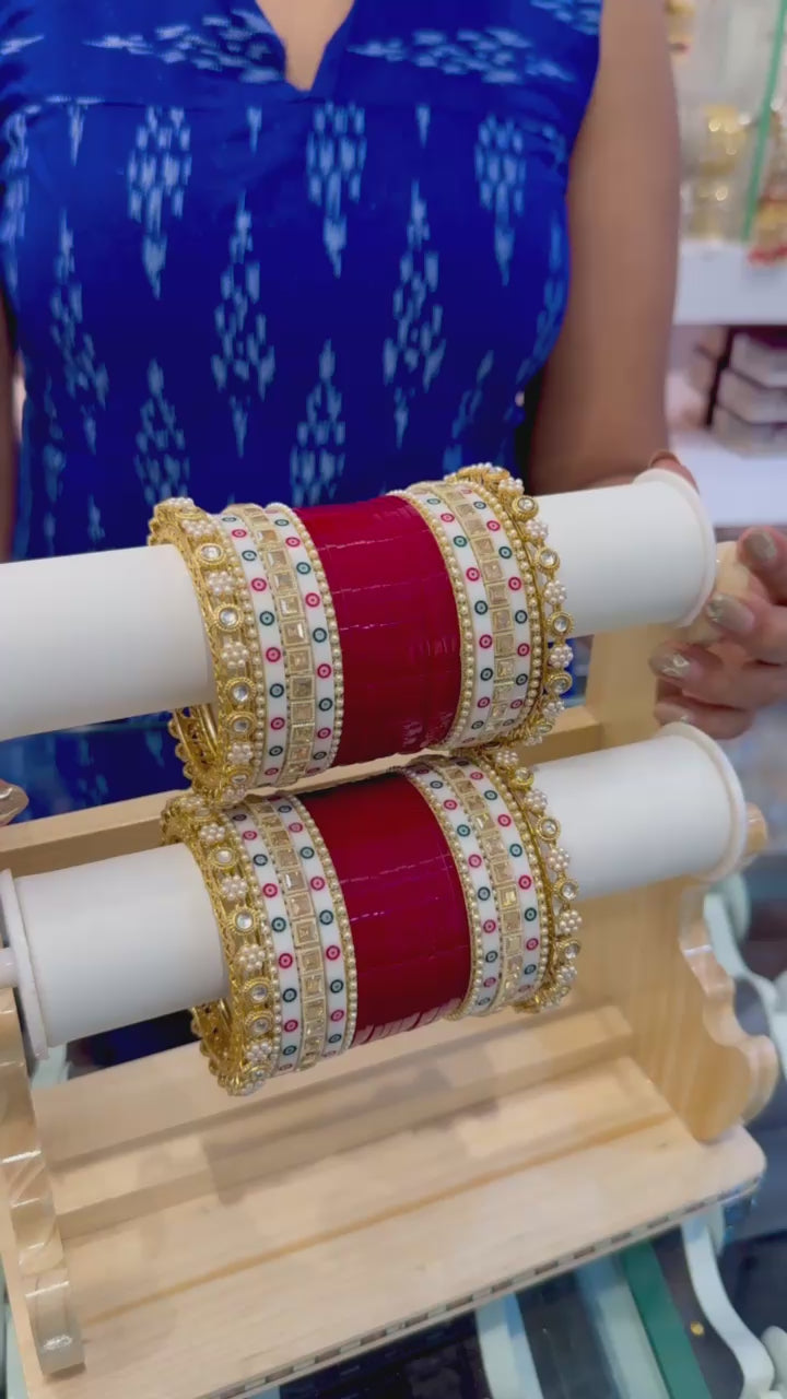 Person wearing red and gold bangles on both wrists with a blue sleeve by hitesh bangles