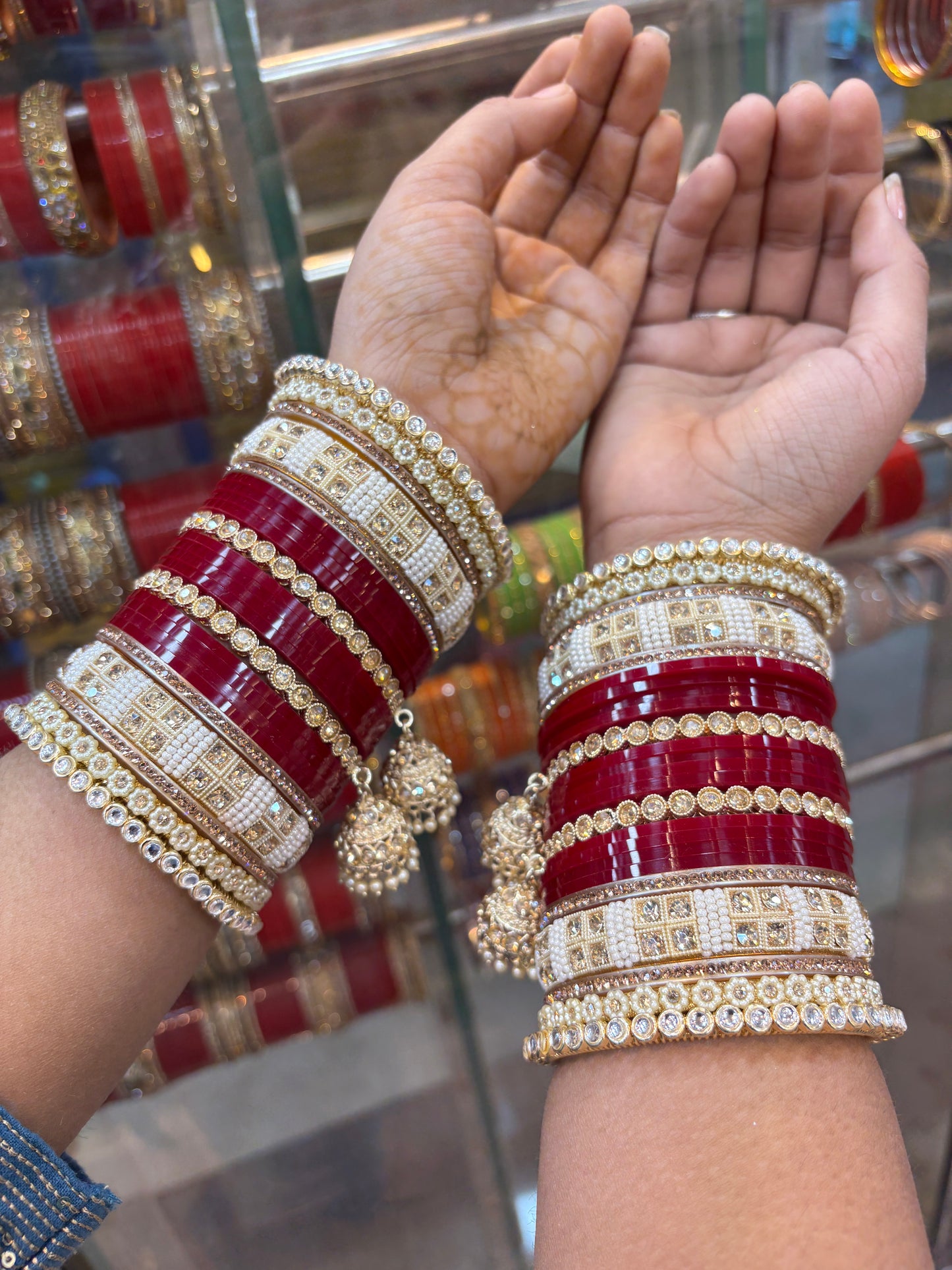 Close-up of hands wearing red and gold bangles with a blurred background by hitesh bangles